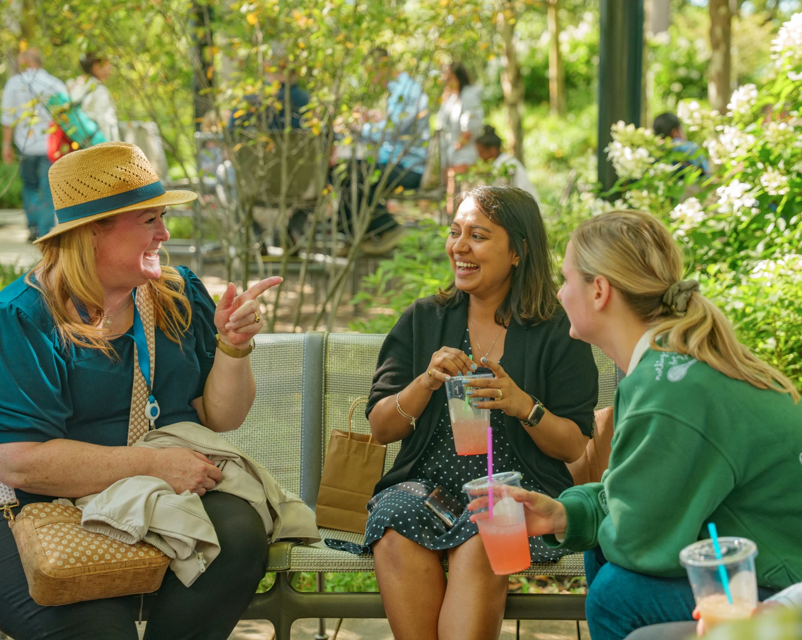 Friends sharing a lively conversation on a park bench surrounded by blooming greenery