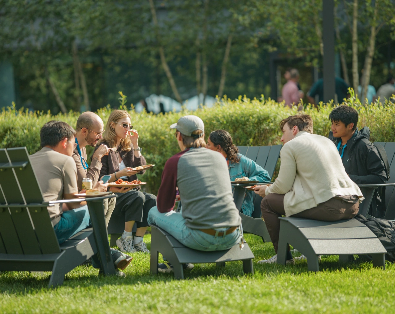 Casual team gathering outdoors with food and conversation in a landscaped office green space
